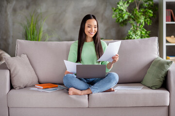 Full body photo of smart asian expert girl sit divan legs crossed folded work remote use laptop read project information in house living room