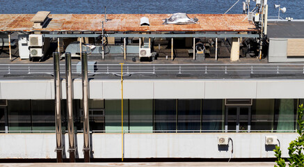 Diverse textures of floors of houses with pipes, rusty roofs of a building and water on a summer day. Chaos architectural concept.