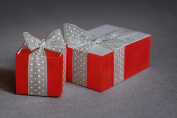 Two red gift boxes wrapped with white bow on neutral background