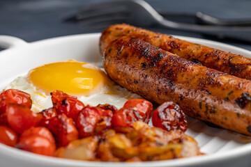 Delicious breakfast with sausage and fried egg combined with tasty caramelized onions and cherry tomatoes.