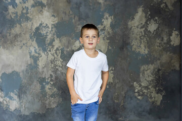 Cute little boy in white t-shirt posing. Portrait of a fashionable male child. Smiling boy posing. The concept of children's style and fashion.

