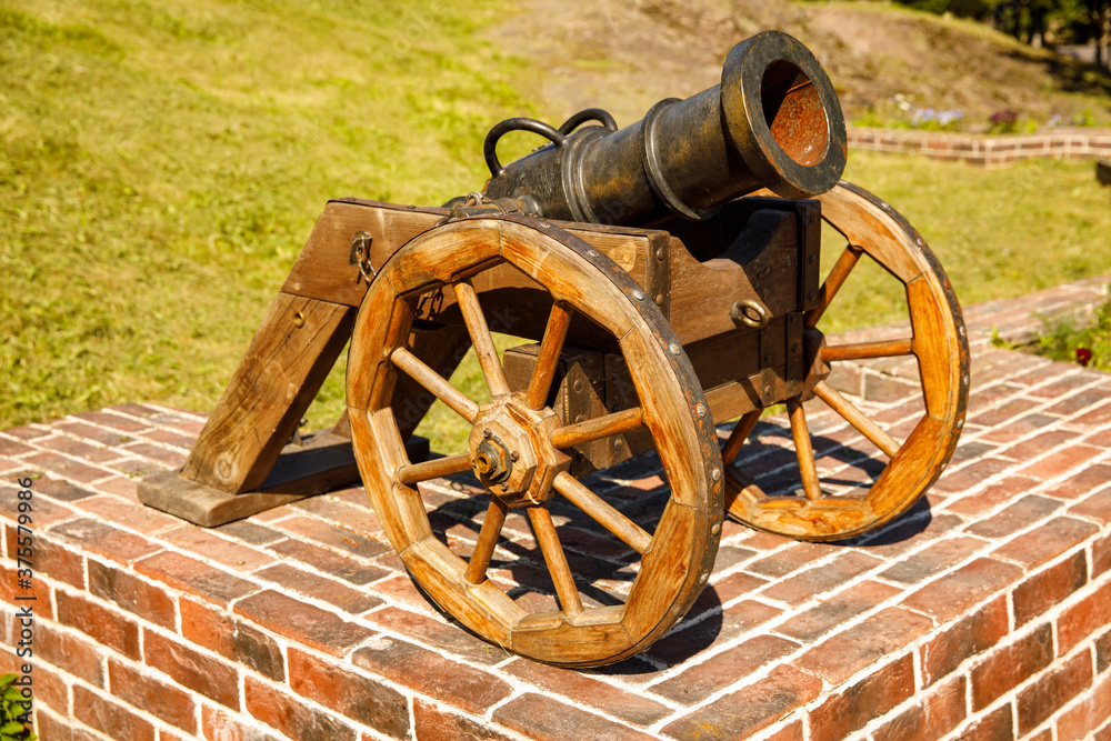 Poster old cannon stands in the park in summer. horizontal frame
