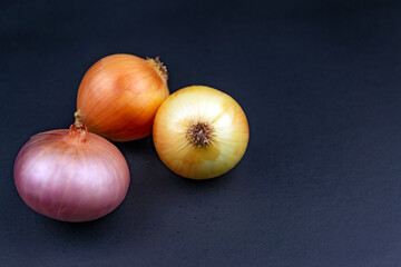 Three onions in husks on a black