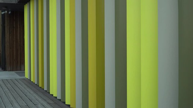 The exterior colourful design sample of the modern house with coloured finishes and wood board cladding on the facade and flooring.