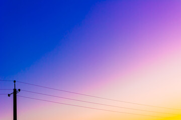 Sunrise and sunset. Bright sky. Twilight colors. Saturation. Light Blue, Blue, Yellow, Purple, Orange. Background with space for text. Power line.