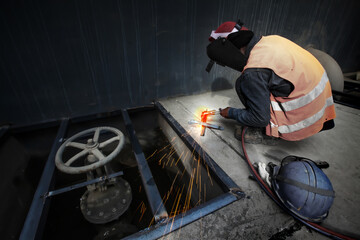 Asian man welding a metal grate.