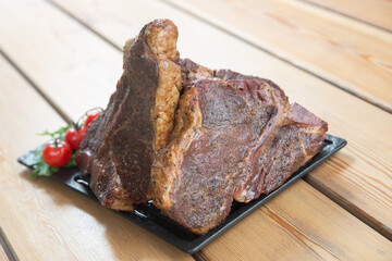 large steak from  grilled t-bone decorated with herbs  tomatoes and salt