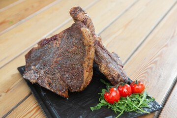 large steak from  grilled t-bone decorated with herbs  tomatoes and salt
