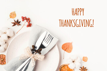 Thanksgiving autumn background. Plate with Cutlery and napkin decorated with autumn leaves, berries and spices. Top view.