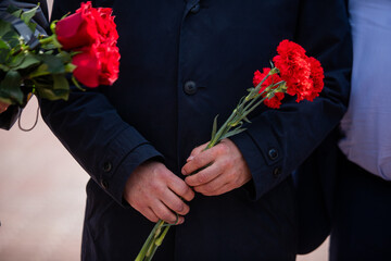 Holds red carnations, a memorable day of mourning.