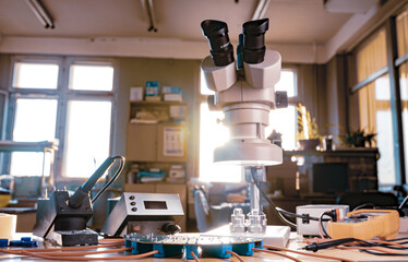 Modern microscope, connectors component and large green microcircuit in workshop laboratory