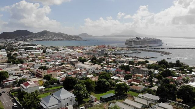 Basseterre / St. Kitts & Nevis - December 2019: Drone backward wide dolly shot of the town with luxury cruise ships docked in the port