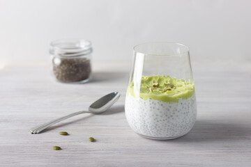 Healthy chia pudding with avocado, spoon and jar with seeds. White background. Healthy breakfast and food concept.