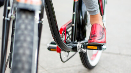 Fototapeta na wymiar woman on retro bike, focus on legs, red shoes