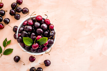 Plate of ripe red cherries with leaves, top view
