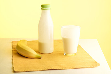 on the table are a banana, a bottle of yogurt and a glass