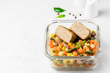Pork patties, cut in half, steamed vegetables in glass container. Copy space.