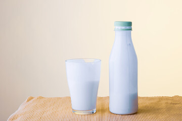 a glass and a bottle of drinking yoghurt are on the table, the back office is yellow