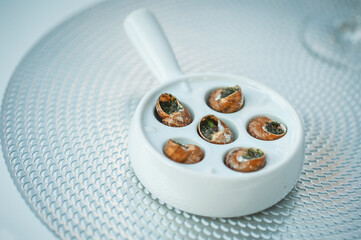 Delicious dish with stuffed snails under different sauces on white background. Dish of snails on a plate close up. Snails baked with butter and spices