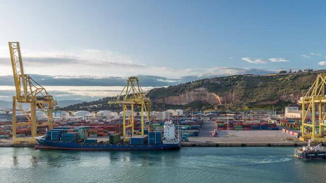 Aerial view of the sea cargo port and container terminal of Barcelona with the Montjuic hill timelapse, Barcelona, Catalonia, Spain. Ships loading by cranes. View from cruise terminal