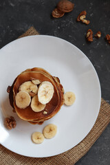 Protein pancakes with banana and walnut on a dark background.