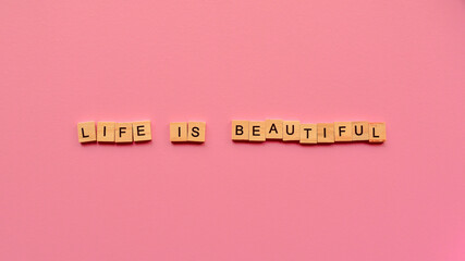 Words "Life is beautiful" on a pink paper background. Motivating web banner.