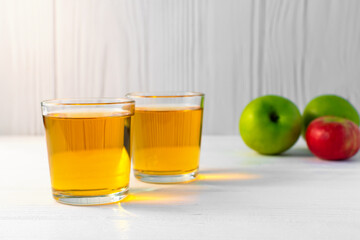 Apple juice in glass and apple on white table. Copy space.