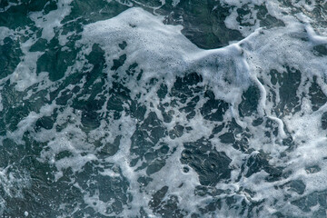         View of wavy sea water with white foam.