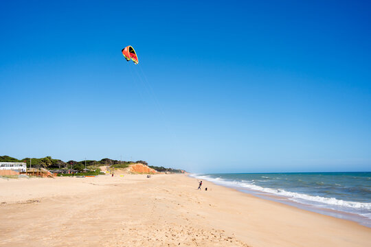 Beautiful kiteboarding surfing with golden sand sea water. Kite in the air on the beach, sunny outdoors background.