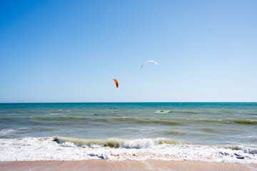 Beautiful kiteboarding surfing with golden sand sea water. Kite in the air on the beach, sunny outdoors background.