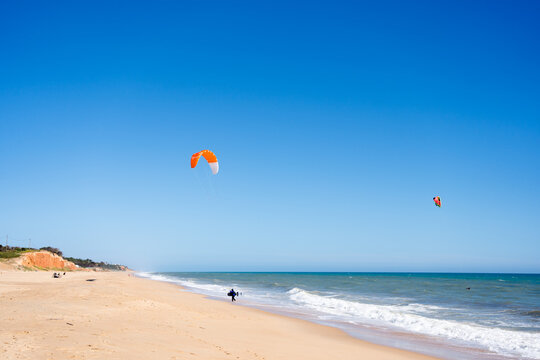 Beautiful kiteboarding surfing with golden sand sea water. Kite in the air on the beach, sunny outdoors background.