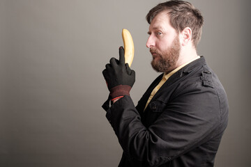 a bearded man holding a banana in his hands mimicking a special services agent