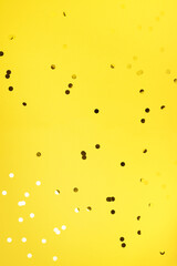 Golden confetti on yellow background with light bokehs. Happy new year celebration party. Greetings and congratulation concept. Festive backdrop with copy space for your design
