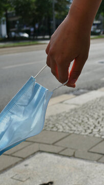 Coronamaske in der Hand einer jungen Frau wedelt im Wind