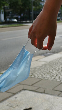 Coronamaske in der Hand einer jungen Frau wedelt im Wind