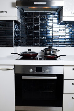 Frying pan on modern black induction stove. Energy efficient electric hob with built-in oven at home kitchen . Close up, copy space, background, top view.