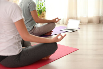 Couple practicing yoga while watching online class at home during coronavirus pandemic, closeup. Social distancing