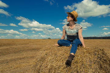 A woman in cowboy hat and yellow sunglasses with wheat rolls