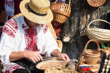 A man makes products from straw.Folk art.Weaving baskets of straw. Craftsman
