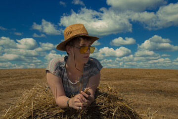Naklejka na ściany i meble A woman in cowboy hat and yellow sunglasses with wheat rolls