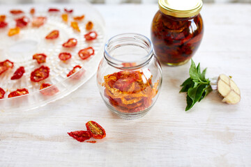 Homemade sun dried tomatoes with herbs, garlic in olive oil in a glass jar
