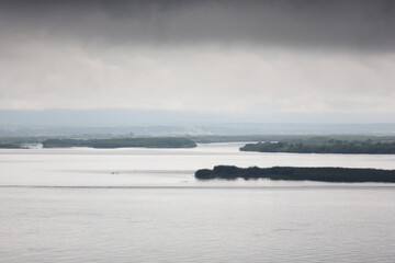 Fototapeta premium Summer thunderous landscape with a river, forest and dark gray dramatic clouds over a river