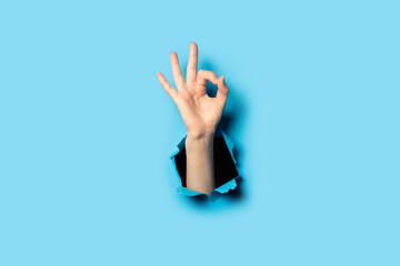 Hand makes a gesture everything is OK on a blue background. Gesture all is well, done
