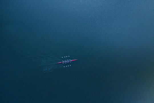 Boat coxed four rowers rowing on the blue river aerial drone top view