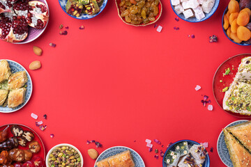 Middle Eastern sweets on red background. Arab dessert, baklava, halva, rahat lokum, sherbet, nuts,...