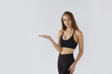 Portrait of a young female athlete on a white background, pointing. Training sports motivation the concept of lifestyle.