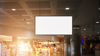 white blank poster with mockup space hangs on chain from ceiling in supermarket or city mall