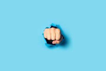 Male fist punches a wall on a blue background. Banner. Breakout gesture, break