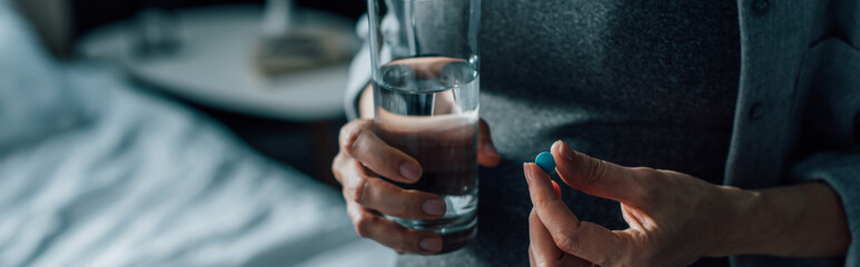 horizontal image of t woman holding glass of water and pill