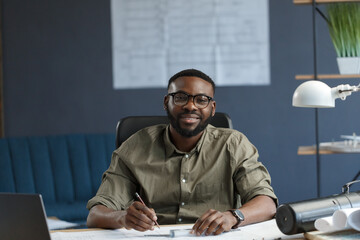 Afro-American architect working in office with laptop.Business portrait of black handsome bearded...